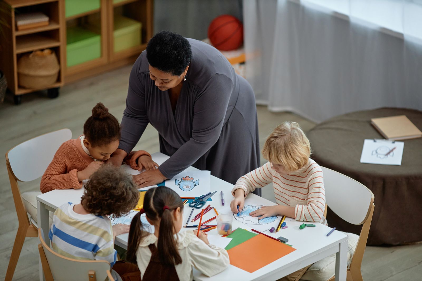 A carer helping young children with an art and craft activity